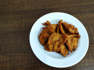 Top view of portion of breaded chicken breast on the wooden table.
