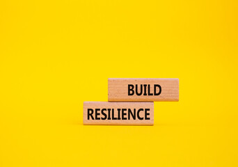 Build resilience symbol. Wooden blocks with words Build resilience. Beautiful yellow background....