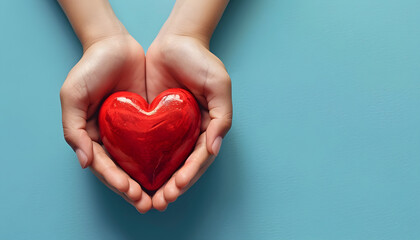 Fototapeta premium Hands holding a red heart on a blue background,