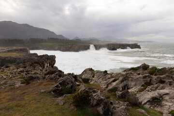 Fototapeta na wymiar Bufones de Pria in Asturias coast on a cloudy day with rough seas and wave spray