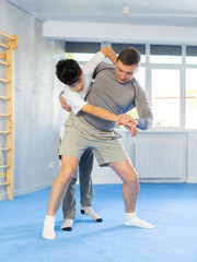 Father teaching his son wrestling or self-defense techniques in the gym