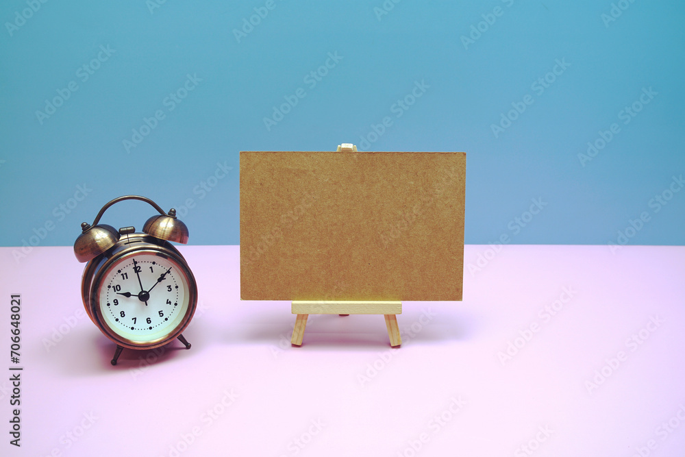 Aufkleber empty card mockup space for text message with wooden easel and vintage alarm clock on pink backgroun