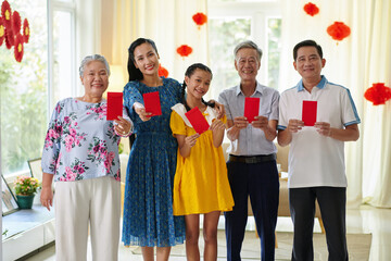 Happy teenage girl with parents and grandparents showing red envelopes with lucky money