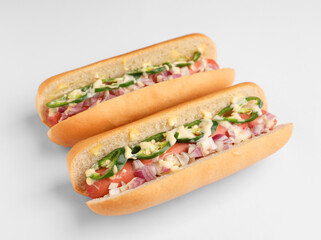 Delicious hot dogs with onion, chili pepper and sauce on white background, closeup
