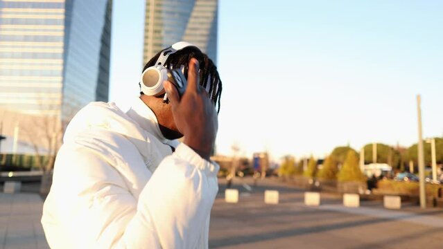 african american boy with dreadlocks wearing headphones listening to music and dancing on the street
