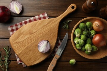 Cutting board with different vegetables, rosemary and knife on wooden table, flat lay