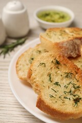 Tasty baguette with garlic and dill on white table, closeup