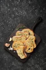 Tasty baguette with garlic, dill and rosemary on grey textured table, top view