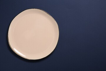 One beige ceramic plate on dark blue background, top view. Space for text