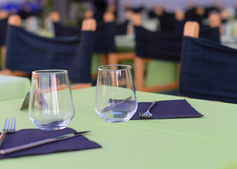 Simple Italian restaurant terrace table setting for two in green and blue, selective focus
