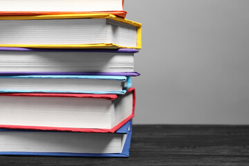 Different books on black wooden table against gray background, closeup. Space for text