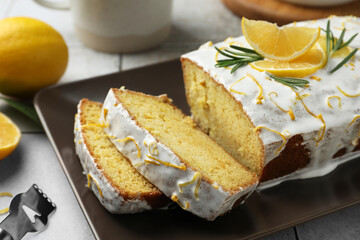 Tasty lemon cake with glaze and citrus fruits on table, closeup