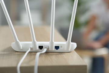 New modern Wi-Fi router on wooden table indoors, closeup
