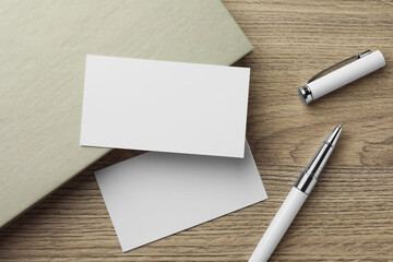 Blank business cards, notebook and pen on wooden table, flat lay. Mockup for design