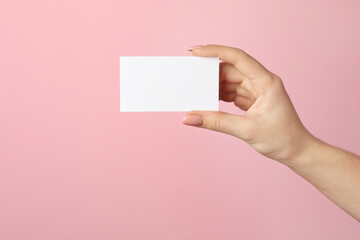 Woman holding blank business card on pink background, closeup. Mockup for design