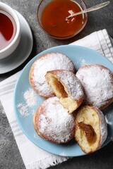 Delicious sweet buns with jam and cup of tea on table, flat lay