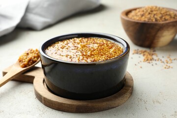 Whole grain mustard in bowl on light table