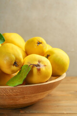 Naklejka na ściany i meble Tasty ripe quince fruits in bowl on wooden table, closeup
