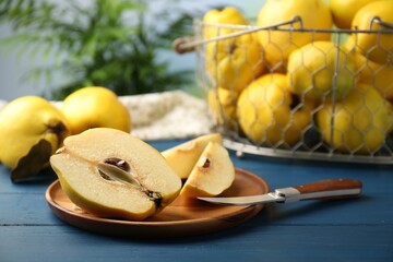 Tasty ripe quince fruits and knife on blue wooden table, closeup