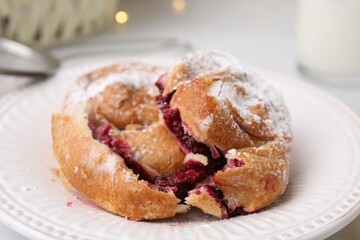 Delicious bun with sugar powder and berries on table, closeup