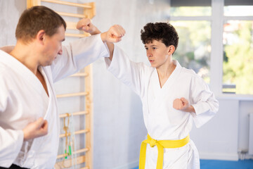 Obraz premium Adult man and teenage boy karatekas training karate fight in studio