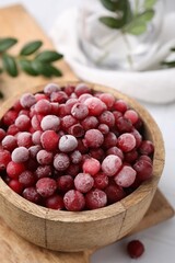 Frozen red cranberries in bowl on table, closeup