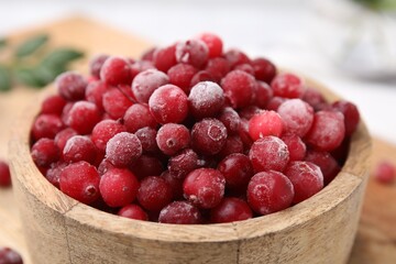 Frozen red cranberries in bowl on table, closeup