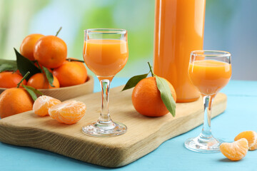 Delicious tangerine liqueur and fresh fruits on light blue wooden table