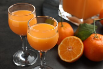 Delicious tangerine liqueur and fresh fruits on grey table, closeup