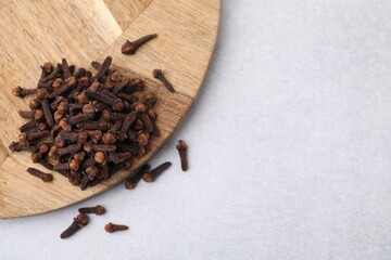 Pile of aromatic cloves on light table, top view. Space for text