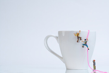 climbers climb a white coffee cup with rope, miniature figures scene,
​