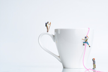 climbers climb a white coffee cup with rope, miniature figures scene,
​