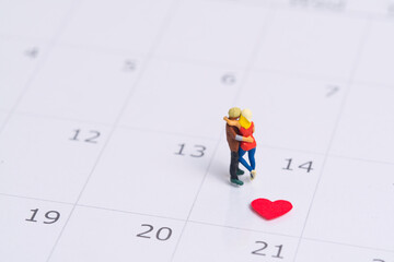 Junges verliebtes Paar steht bei der Nummer 14 auf einem Kalender im Monat Februar wegen Valentinstag , Miniaturfiguren szene