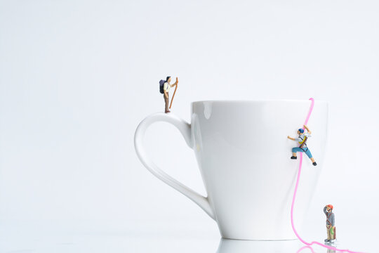 climbers climb a white coffee cup with rope, miniature figures scene,
​
