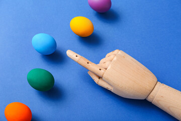 Decorative wooden hand with Easter eggs on blue background