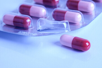 Pill and blister pack. Medicine capsule removed from its packaging. Cold colors, selective focus.