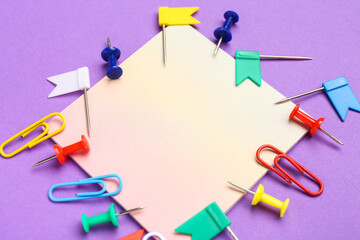 Sticky note and paperclips on purple background