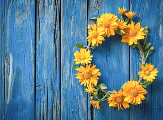 Yellow Flowers Arranged in a Heart Shape on Blue Wooden Background