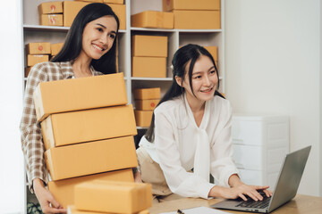 Two asian women with startup small business entrepreneur freelance working at home. checking product order. Online woman sellers working for e-