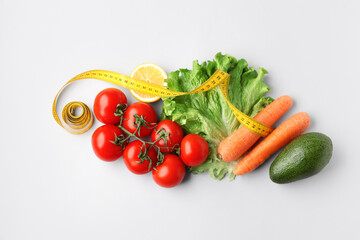 Vegetables, lemon and yellow measuring tape on grey background. Diet concept
