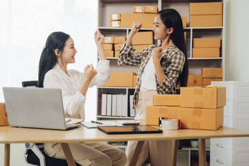 Two businesswomen celebrating online sales success in office. Concept of e-commerce and achievement