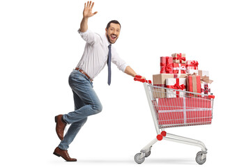 Excited businessman running with presents in a shopping cart and waving at camera