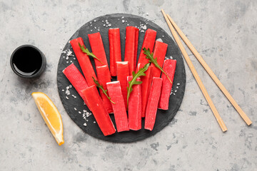 Slate board with tasty crab sticks and sauce on grunge background © Pixel-Shot