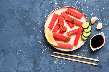 Plate with tasty crab sticks and sauce on blue background © Pixel-Shot