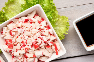 Bowl with tasty chopped crab sticks on light wooden background, closeup © Pixel-Shot