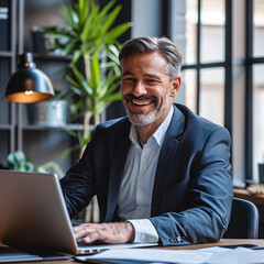 Fototapeta premium Executive Focus: Gray-Haired Businessman Engaged in Work, Seated Before His Laptop - A Portrait of Professional Acumen and Business Dedication - Generative AI
