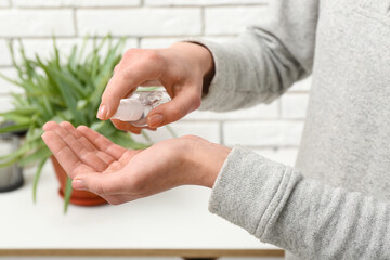 Woman applying sanitizer on her hands at home, closeup