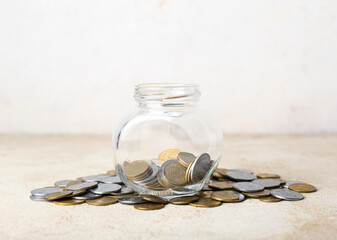 Jar with coins in beige grunge table. Savings concept