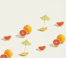 A seamless pattern made of isolated grapefruits, oranges and lemons with a cocktail parasol on a beige background