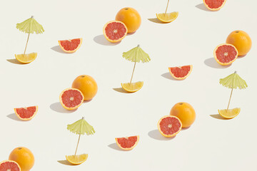 A seamless pattern made of isolated grapefruits, oranges and lemons with a cocktail parasol on a...